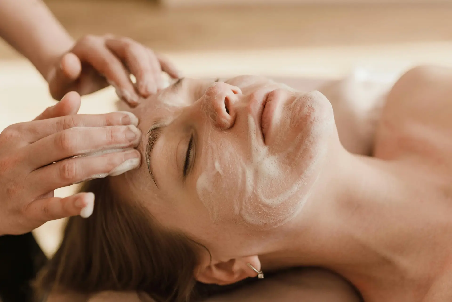 Welcome Home 30 A close-up of a woman receiving a soothing facial massage with a skincare mask.